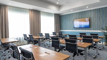 Un salón de conferencias con una gran pantalla de televisión, varias mesas y sillas.