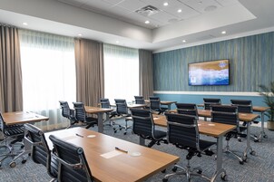 Un salón de conferencias con una gran pantalla de televisión, varias mesas y sillas.