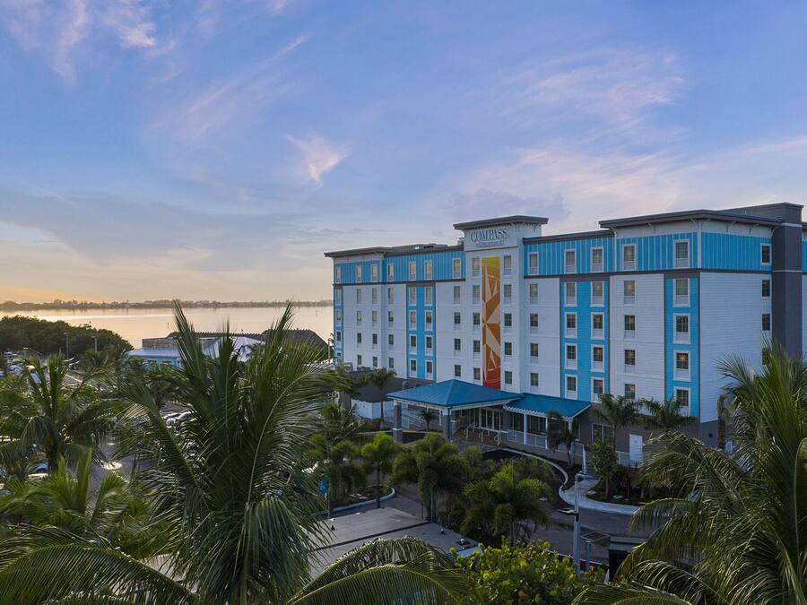 A multi-story hotel with a blue and white facade, located near a body of water.
