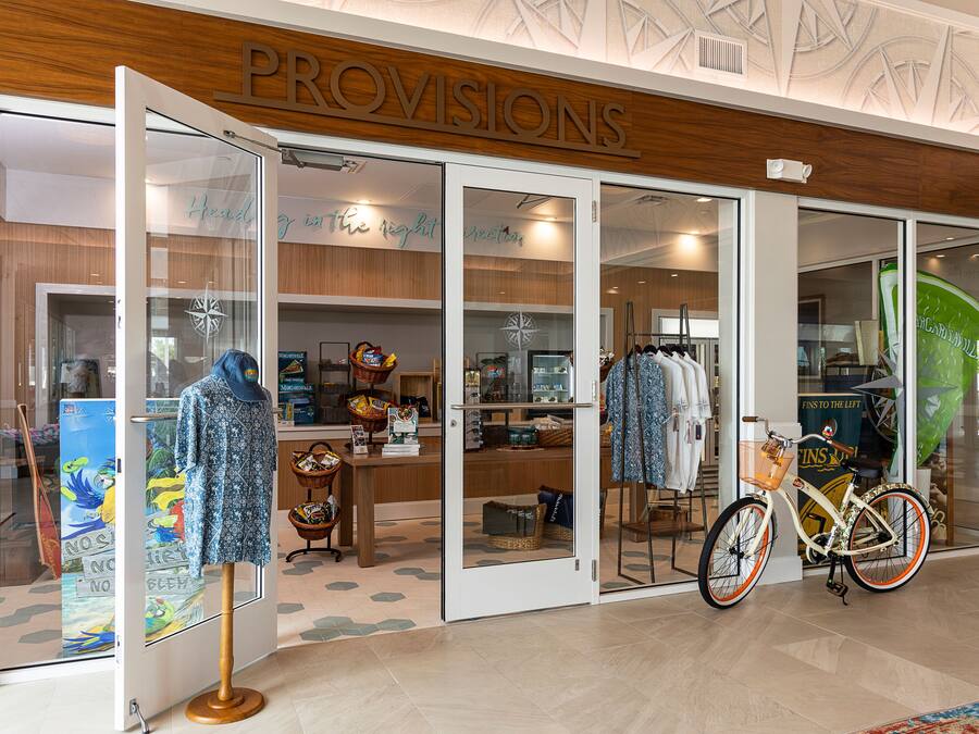En butik som heter ”PROVISIONS” med glasdörrar, en cykel och diverse varor inuti.