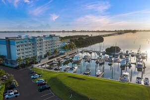 A marina with boats docked, a hotel with multiple floors, and a long pier extending into the water.
