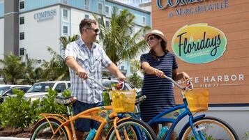 Dos bicicletas estacionadas frente a un edificio con un letrero que dice "Compass by Margaritaville" y "Flordays Woodfire Grill & Bar".