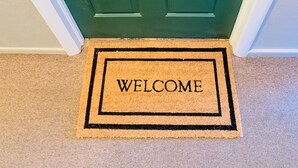 Eine grüne Tür mit der Aufschrift "GREEN MILE" und einem Sternsymbol, einem Zahlenschloss und einer Fußmatte mit der Aufschrift "WELCOME".