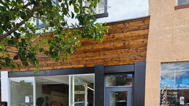 Ein Schaufenster mit Holzfassade, großen Glasfenstern und einem blauen Pfeil auf dem Bürgersteig.