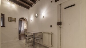 A room with a table and chairs, a radiator, a door, and a framed picture on the wall. - GuestHost - Rione Monti & Fori Imperiali Elegant Apartment x3 (Roma)