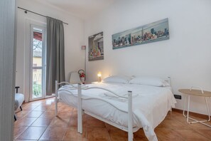 A bedroom with a bed, a chair, a table, a painting, and a fire extinguisher. - GuestHost - Cozy and bright 70 sqm apartment, structured on two levels and located on the ground floor of a renovated period building. Perfect for 5 people, the accommodation enjoys an ideal location to easily reach any monument in the historic city cent (Ferrara)