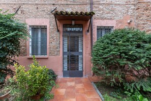 A stone building with a tiled entrance, a metal gate, and a small window with bars. - GuestHost - Cozy and bright 70 sqm apartment, structured on two levels and located on the ground floor of a renovated period building. Perfect for 5 people, the accommodation enjoys an ideal location to easily reach any monument in the historic city cent (Ferrara)