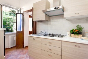 A kitchen with a gas stove, sink, and wooden cabinets. - GuestHost - Cozy and bright 70 sqm apartment, structured on two levels and located on the ground floor of a renovated period building. Perfect for 5 people, the accommodation enjoys an ideal location to easily reach any monument in the historic city cent (Ferrara)