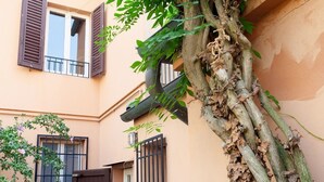 A building with a tree growing against the wall, a gate, and a window with shutters. - GuestHost - Ferrara Lilac Casa dell'Archivòlto with Garage (Ferrara)