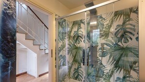 A glass-enclosed shower with a tropical leaf pattern, a staircase, and a wooden bench. - GuestHost - Ferrara Lilac Casa dell'Archivòlto with Garage (Ferrara)