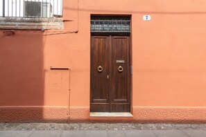 A double wooden door with a metal grille, a small step leading up to it, and a number '7' on the wall to the right. - GuestHost - Ferrara Lilac Casa dell'Archivòlto with Garage (Ferrara)