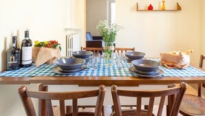 A dining table with a checkered tablecloth, several bowls, glasses, and bottles of wine. - GuestHost - Ferrara Lilac Casa dell'Archivòlto with Garage (Ferrara)
