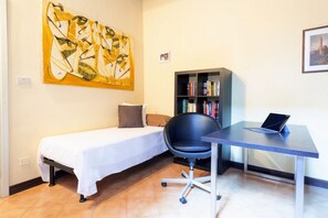 A small room with a bed, a desk with a laptop, a chair, a bookshelf, and a large painting on the wall. - GuestHost - Ferrara Lilac Casa dell'Archivòlto with Garage (Ferrara)