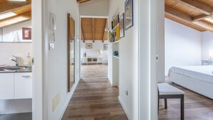Un interior moderno con techo de madera, una cocina con armarios blancos y una zona de comedor con mesa y sillas blancas.