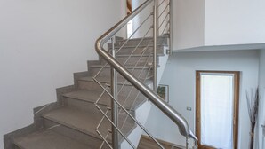 Una escalera con barandilla metálica, una puerta de madera y un cuadro en la pared.