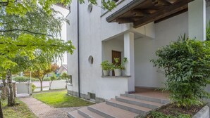 Un edificio moderno con fachada blanca, un sendero de ladrillos y escalones que conducen a una entrada cubierta.