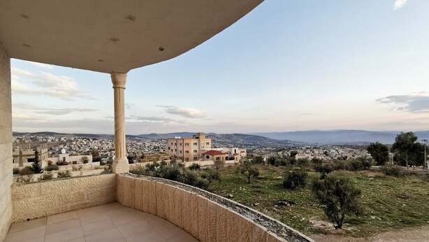 A balcony with a view of a cityscape, including buildings and distant mountains. - Jerash Inn (Jerash)