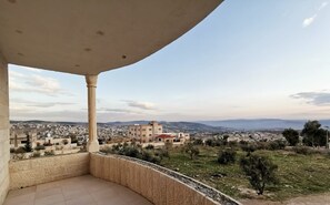 Un balcón con vistas a un paisaje urbano, incluyendo edificios y montañas distantes.