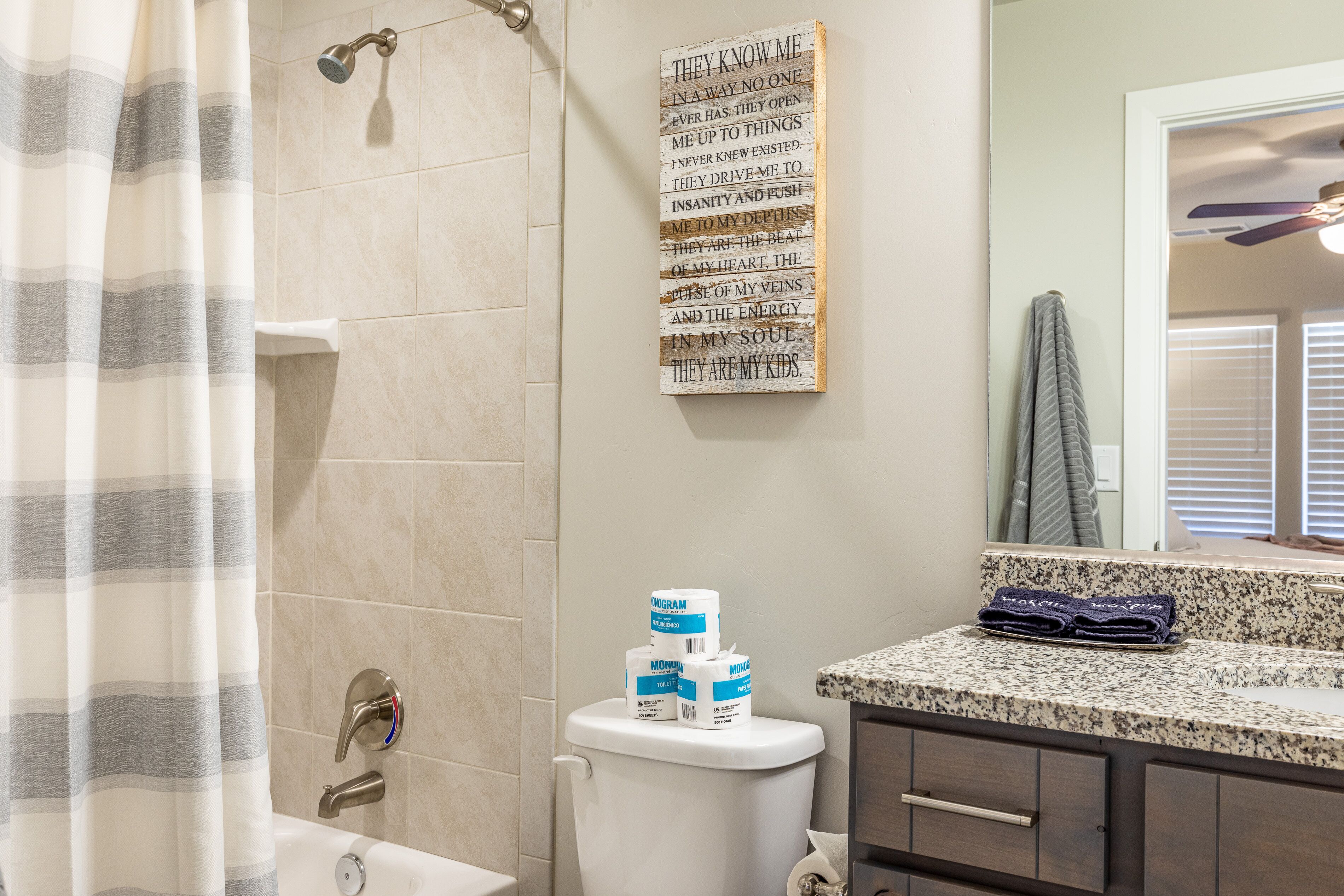 A bathroom with a shower, toilet, and a vanity with a mirror.