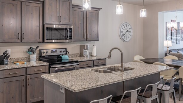 Una cocina moderna con encimeras de granito, electrodomésticos de acero inoxidable y una isla grande con asientos tipo barra.