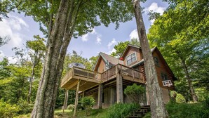 A log cabin with a wooden deck and stairs leading to the entrance. - Luxurious Log Cabin with Stunning Views (Sugar Mountain)