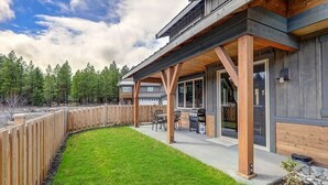Una casa moderna con un porche cubierto, terraza de madera y jardín cuidado.