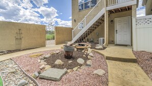 Una casa de dos pisos con fachada de piedra, una chimenea en el patio trasero y una escalera que conduce al segundo piso.