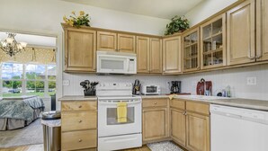Una cocina con armarios de madera, microondas, estufa y lavavajillas.