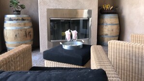 Een gezellig buitenverblijf met rieten meubilair, een open haard en decoratieve vaten.