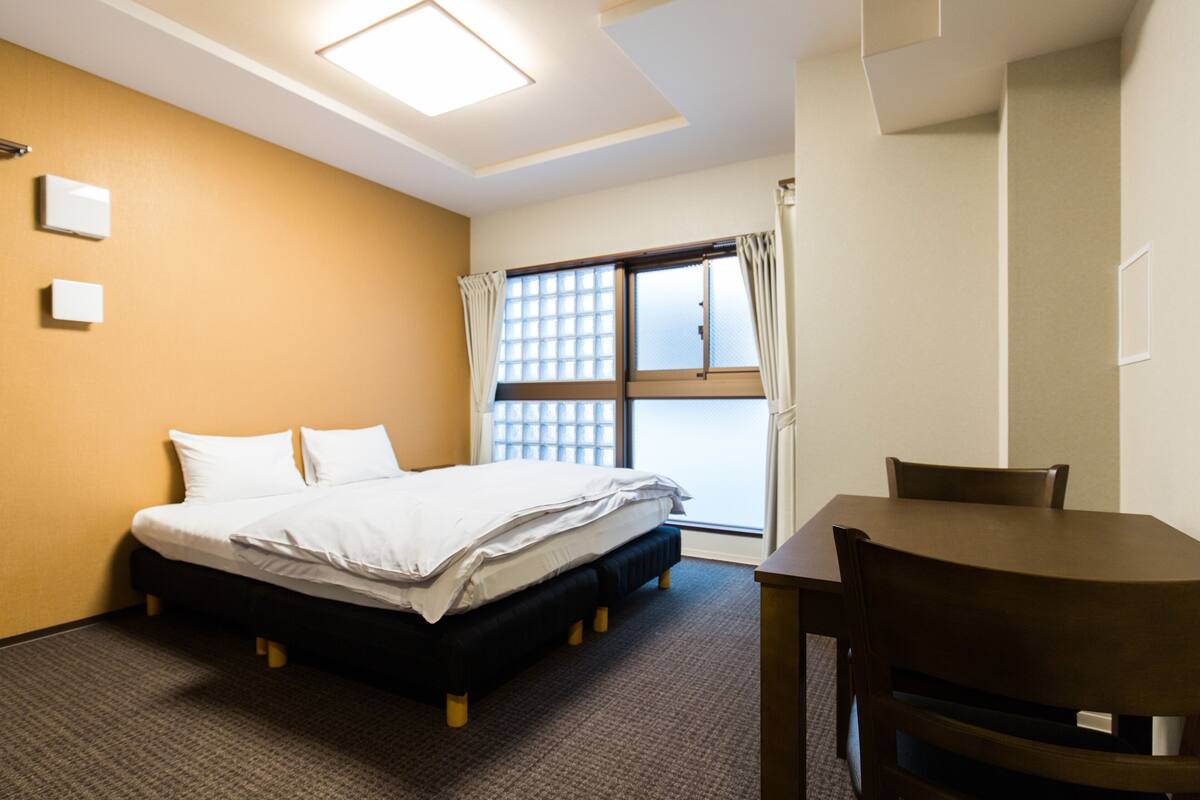 Ein Hotelzimmer mit Bett, Tisch und einem fenster mit Vorhängen.