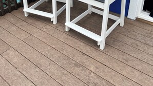 To Adirondack-stole med hvide stel og mørke sæder på en træterrasse.