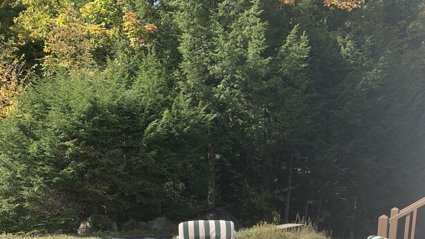 Un área de estar al aire libre con cuatro sillas y una mesa cuadrada con una chimenea.