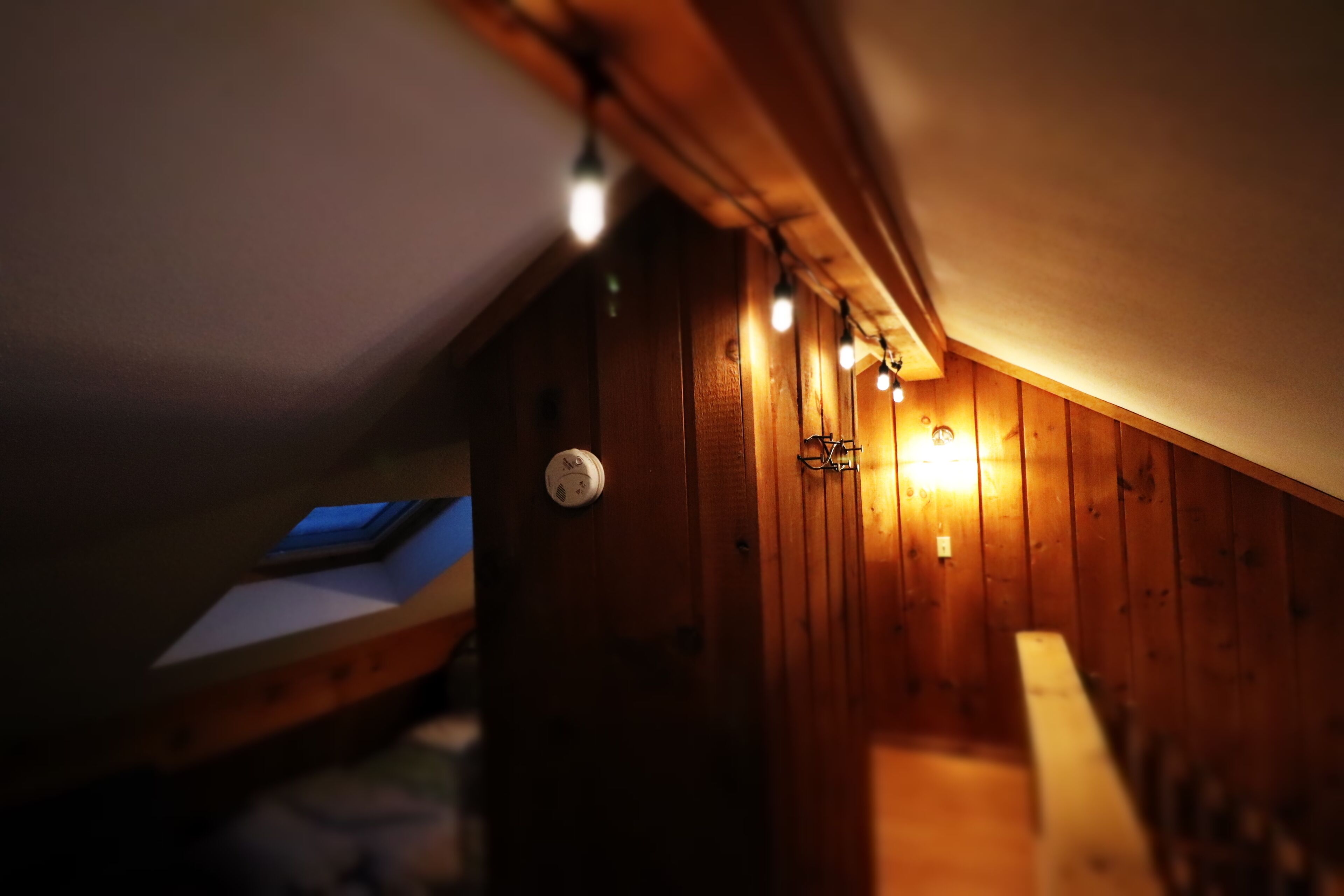 Un petit grenier étroit aux murs en bois et aux plafonds inclinés.