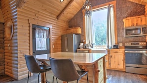 A log cabin with a kitchen featuring a central island, bar stools, a refrigerator, a microwave, and an oven. - Family Size Cabin with Kitchen, Fireplace, Hot Tub (Millersburg)
