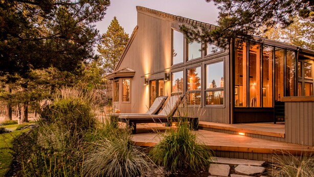 Een modern huis met grote ramen, een terras en een pad van natuursteen.