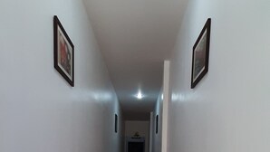 A corridor with white walls, red tiles, and framed pictures on the walls. - Sala Bua Room Karon (Karon)