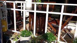 A balcony with potted plants, wooden furniture, and a 'No Entry' sign. - Sala Bua Room Karon (Karon)