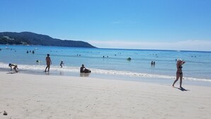 A beach with people swimming and walking on the sand. - Sala Bua Room Karon (Karon)