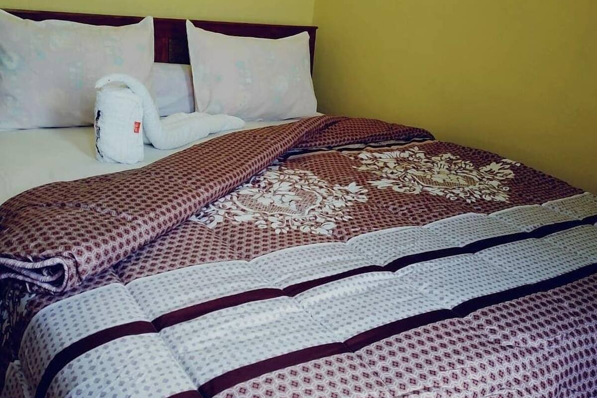 A hotel room with a bed, pillows, and a blanket.