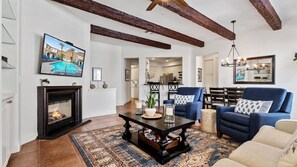 Cozy living room with a fireplace, TV, and pool view.