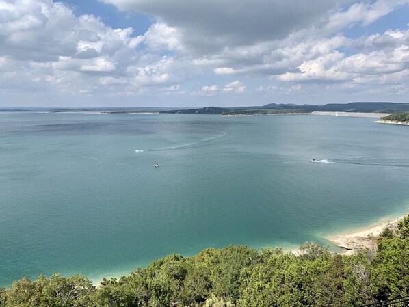 Paesaggio costiero con acque turchesi cristalline, una spiaggia sabbiosa e vegetazione lussureggiante.