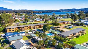 A residential area with multiple apartment buildings, a swimming pool, and a view of a lake and mountains.