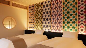Ett hotellrum med två sängar, en rund spegel på väggen och en dekorativ panel med geometriska mönster.
