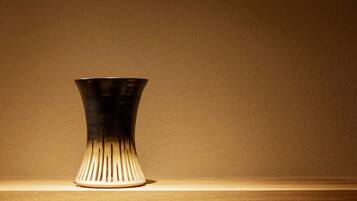 A metallic vase with a tapered design on a wooden surface against a plain wall.