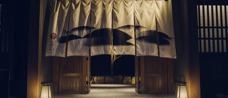 A traditional Japanese entrance with tatami mats, a shoji screen, and lanterns.