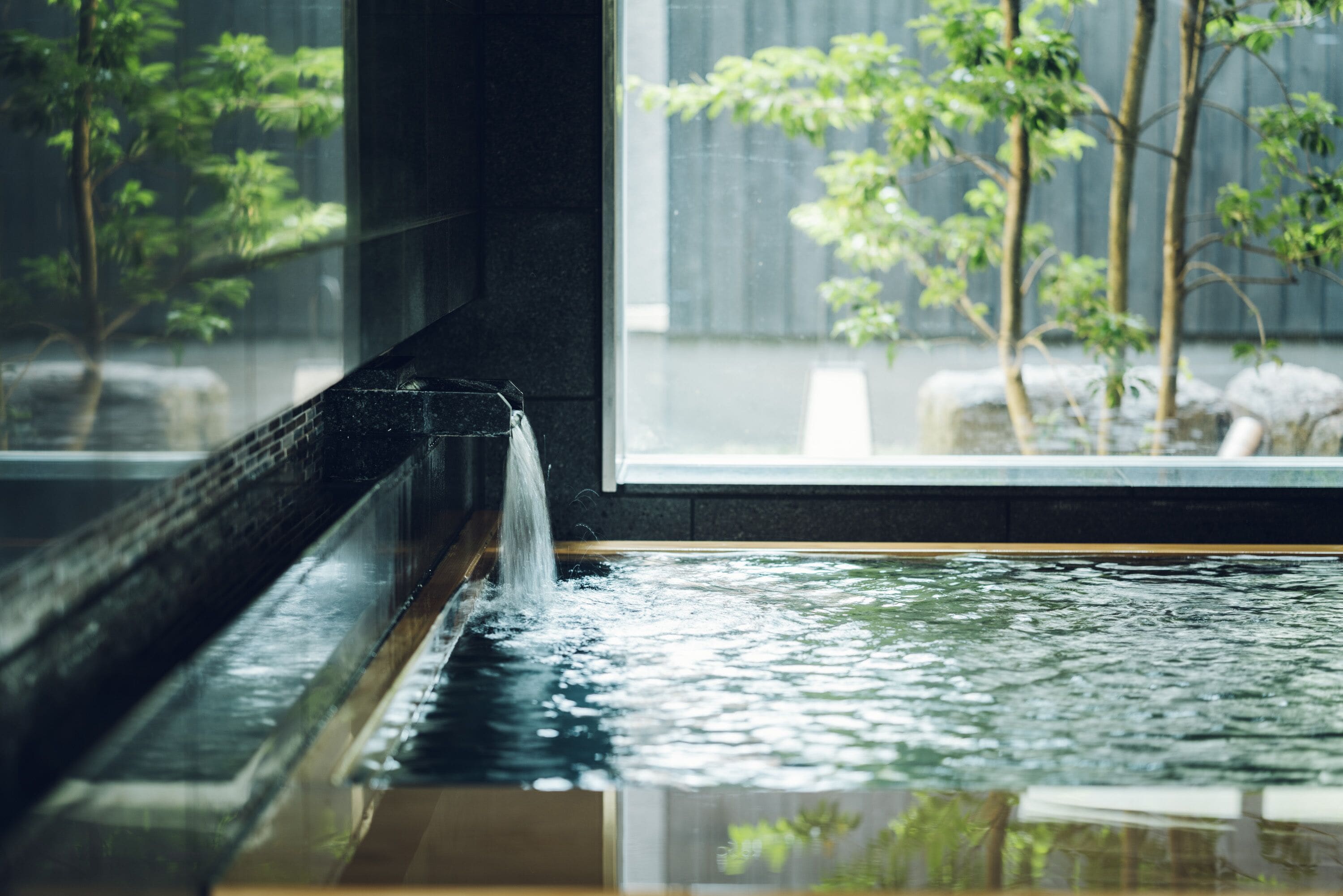 A water feature in a modern indoor setting with a view of trees outside.