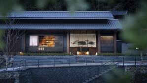 Ein traditionelles japanisches Gebäude mit einem Ziegeldach, einer Steinmauer und einem hölzernen Eingang.