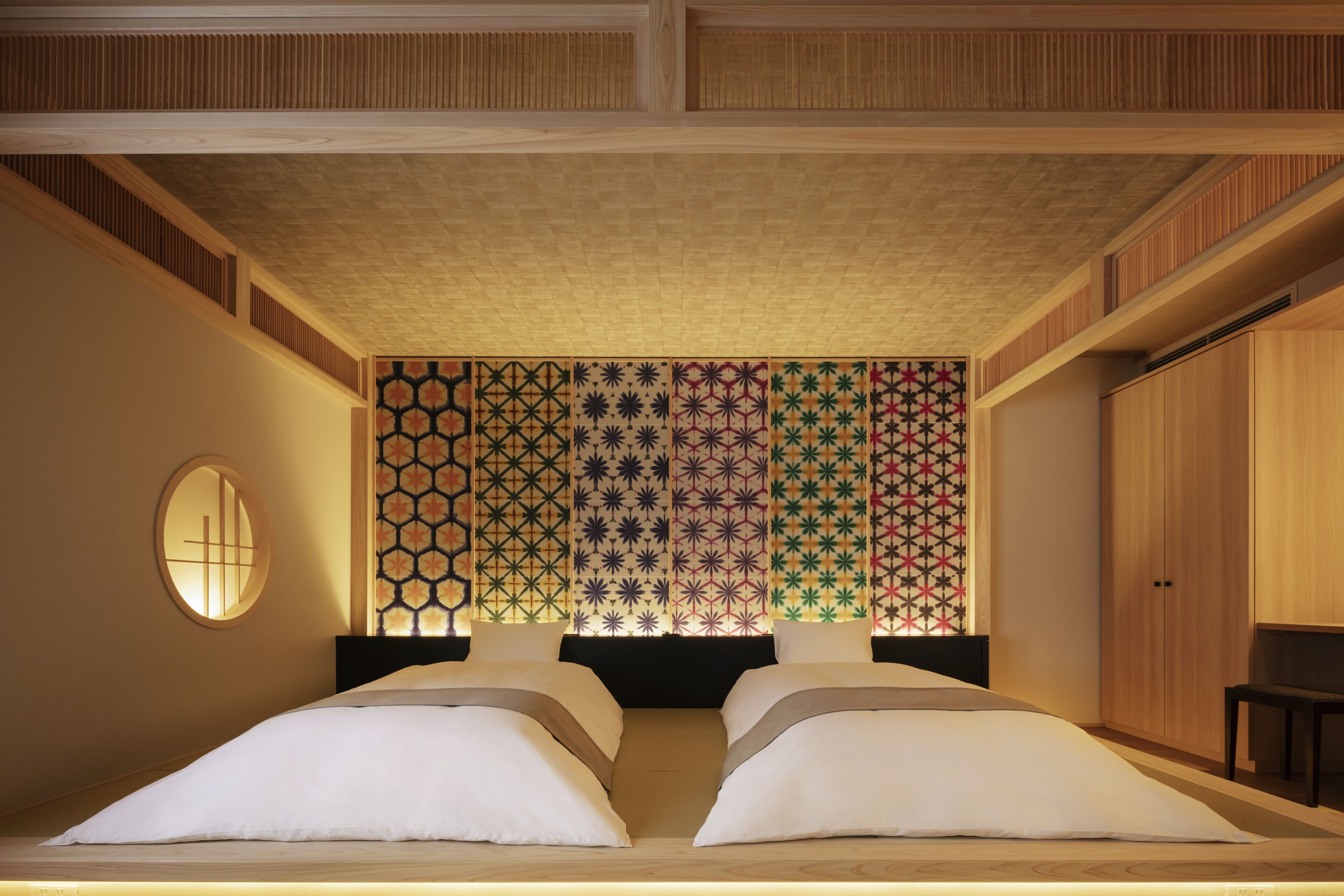 Una habitación de hotel con una cama grande, un espejo redondo y un papel tapiz estampado.