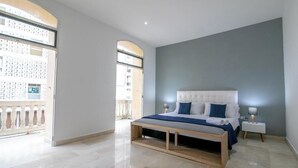 Een slaapkamer met een groot bed, een nachtkastje en een raam met uitzicht op een gebouw.