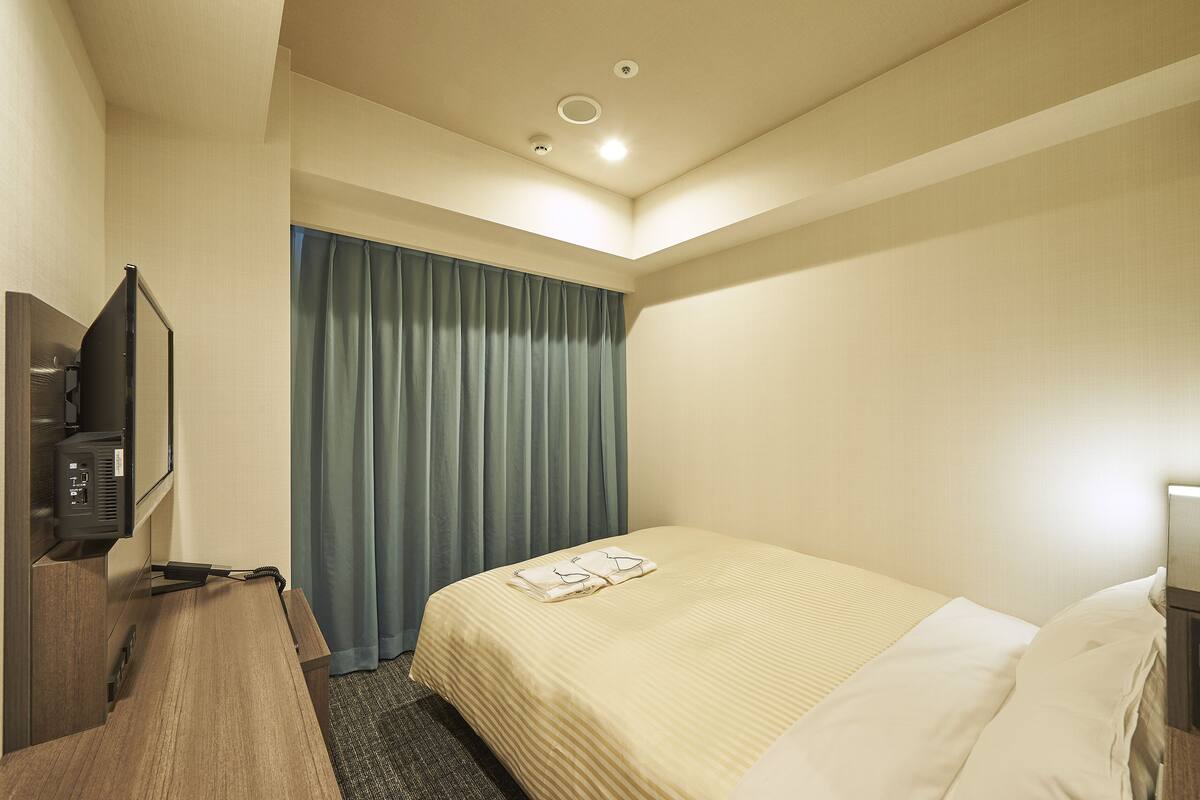 A hotel room with a bed, a TV, and a desk.